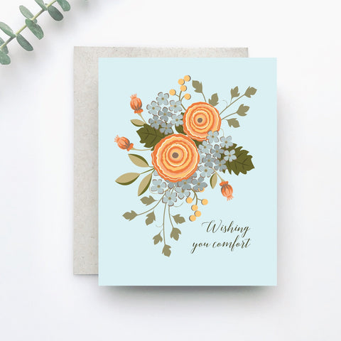 A pretty gathering of illustrated florals in apricot and blue is gathered together on a background of soft pastel blue, with wishes for comfort